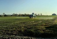 Zdjęcie przedstawia opryskiwacz podczas pracy na polu