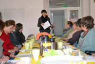 kobieta przemawiająca do grupy kobiet siedzących przy stole