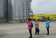 trójka kobiet stojąca pod dużymi srebrnymi silosami na terenie biogazowni